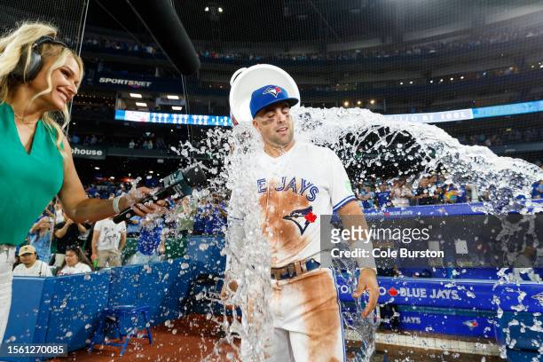 Whit Merrifield of the Toronto Blue Jays gets an ice bath from Vladimir Guerrero Jr. #27 during his post game interview after a 4-1 win over the Los...