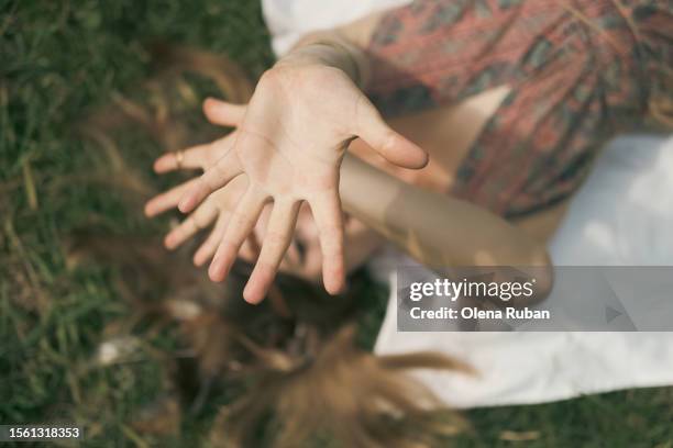 young woman shielding from the sun while lying on the grass. - hands sun stock-fotos und bilder
