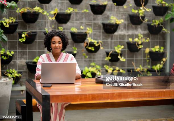 beautiful african woman working on a laptop in a coffee shop - green building stock pictures, royalty-free photos & images