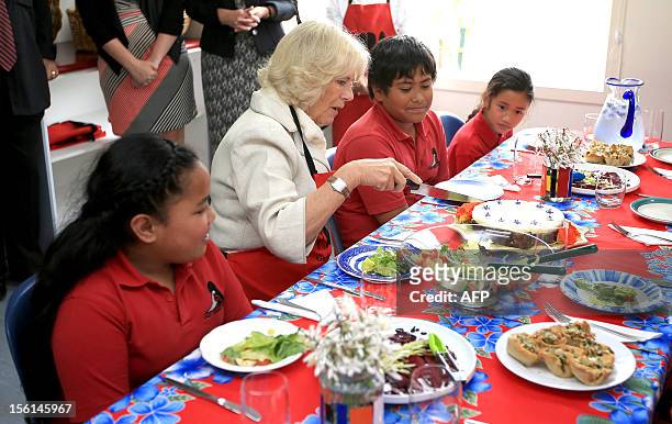 Britain's Duchess of Cornwall, Camilla , cuts slices of carrot cake for lunch during a visit to East Tamaki Primary School, in Auckland on November...