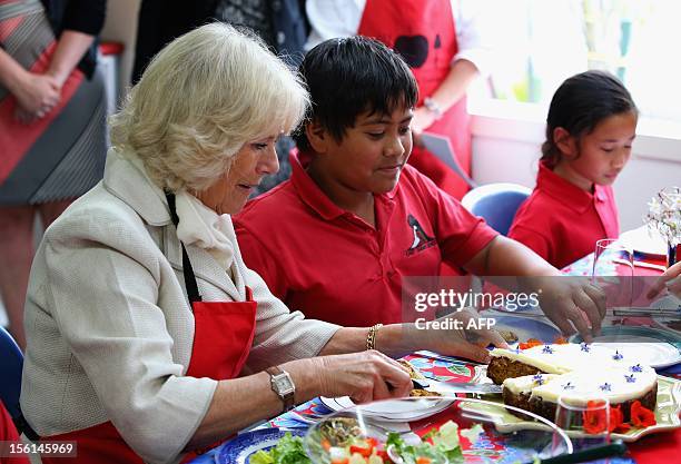 Britain's Duchess of Cornwall, Camilla , cuts slices of carrot cake for lunch during a visit to East Tamaki Primary School, in Auckland on November...