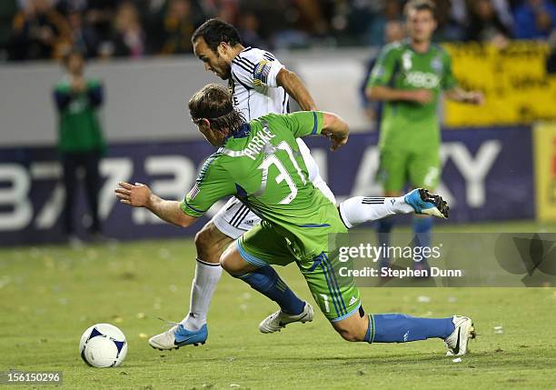Landon Donovan of the Los Angeles Galaxy carries the ball around Jeff Parke of the Seattle Sounders on his way to setting up Robbie Keane for the...
