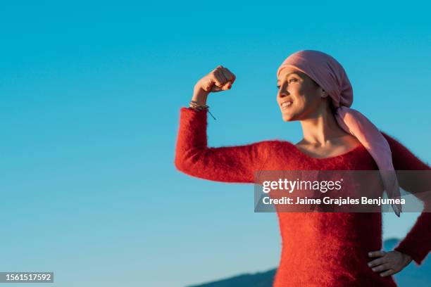 gesunde frau zeigt ihre faust der macht gegen weiblichen krebs - überleben stock-fotos und bilder