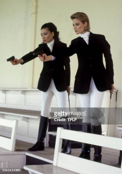 English actress Papillon Soo Soo, is Pan Ho and Irish actress Alison Doody, is Jenny Flex, dressed in costumes, point their guns in the stands at...