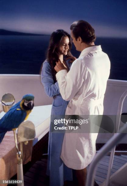 French actress Carole Bouquet, is Melina Havelock and English actor Roger Moore , is James Bond, stand on a boat together during the filming of the...