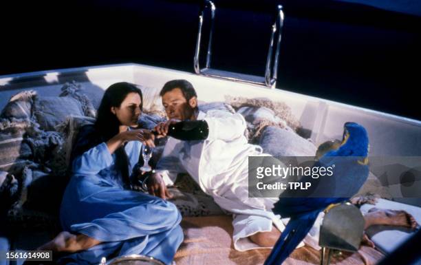 French actress Carole Bouquet, is Melina Havelock and English actor Roger Moore , is James Bond, lay on a boat together during the filming of the...