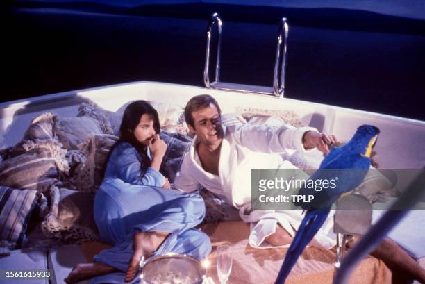French actress Carole Bouquet, is Melina Havelock and English actor Roger Moore , is James Bond, lay on a boat together during the filming of the...
