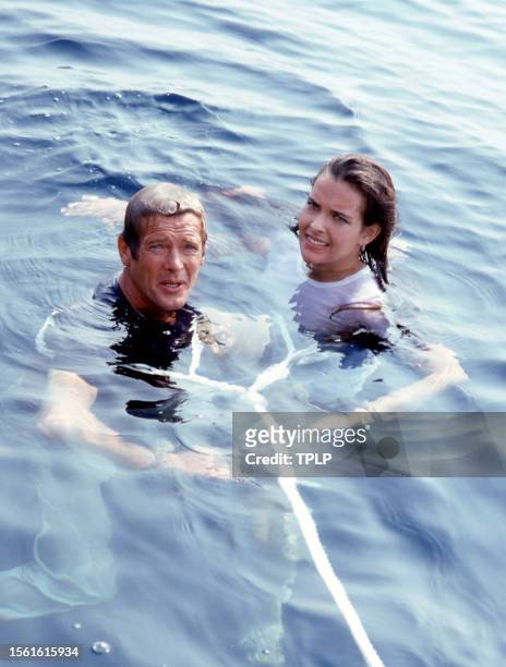 English actor Roger Moore , is James Bond and French actress Carole Bouquet, is Melina Havelock, stand tied together during the filming of the 1981...