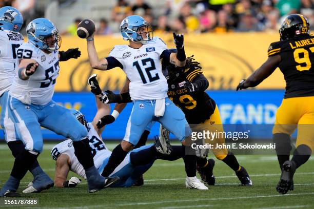 Chad Kelly of the Toronto Argonauts throws a pass as he is hit by Tre' Crawford of the Hamilton Tiger-Cats during the first half at Tim Hortons Field...