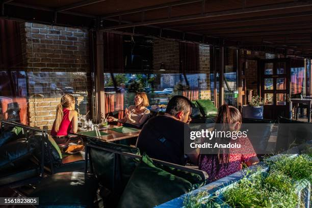 People sit and chat at a cafe while daily life continues at public places as the war with Russia has been going on for more than 18 months in Kyiv,...