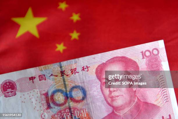 In this photo illustration, a 100 RMB banknote is displayed with the Chinese flag in the background.