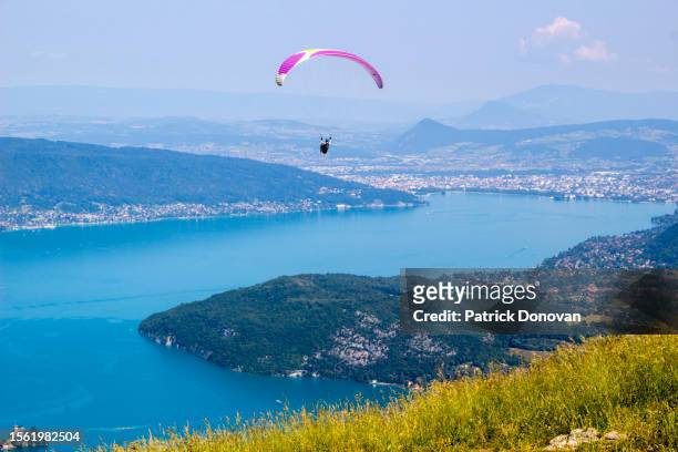 paraglider over lac d'annecy seen from talloires-montmin, france - lac d'annecy photos et images de collection