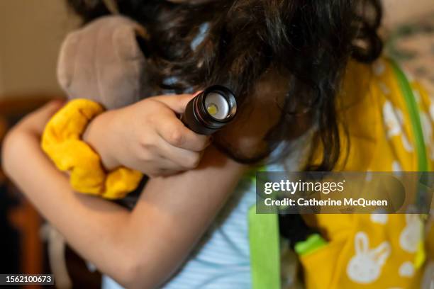cute young multiracial girl holds a flashlight, stuffed animal & wears a backpack ready to explore - chasse au trésor photos et images de collection