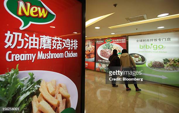 People look at advertisements outside restaurants in Beijing, China, on Friday, Nov. 9, 2012. China's retail sales exceeded forecasts and inflation...