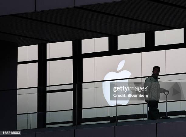 Worker walks past the Apple Inc. Logo in the Sanlitun area of Beijing, China, on Friday, Nov. 9, 2012. China's retail sales exceeded forecasts and...