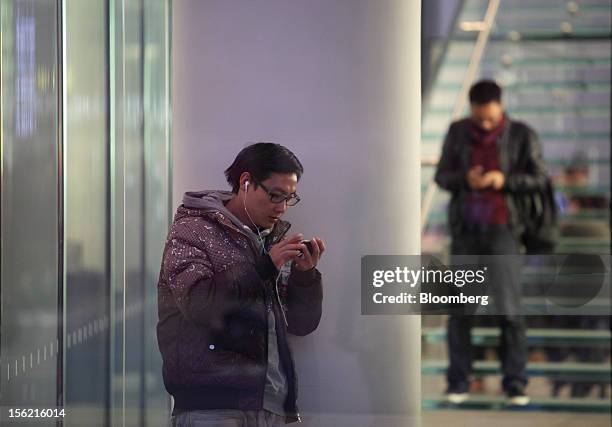 Men use smartphones in the Sanlitun area of Beijing, China, on Friday, Nov. 9, 2012. China's retail sales exceeded forecasts and inflation...