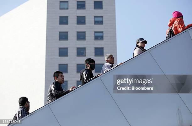 Pedestrians and shoppers ride on an escalator in Beijing, China, on Sunday, Nov. 11, 2012. Chin's retail sales exceeded forecasts and inflation...