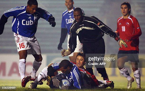 Roberto Gutierrez de Chile, disputa el balón en el piso con Silvio Miñoso de Cuba, observado por el arquero caribeño Edelin Molina y el defensa...