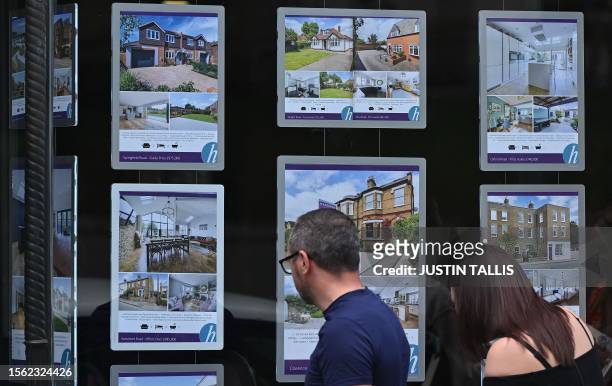 Pedestrians look at residential properties displayed for sale in the window of an estate agents' in Windsor, west of London, on July 29, 2023....