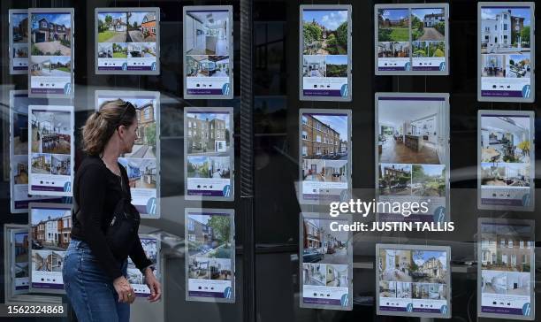 Pedestrians looks at residential properties displayed for sale in the window of an estate agents' in Windsor, west of London, on July 29, 2023....