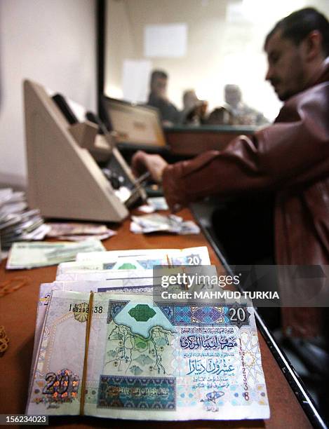 Libyan dinars lie on the desk of a clerk at a bank in the Libyan capital Tripoli on February 16, 2012. Oil exports are approaching pre-conflict...