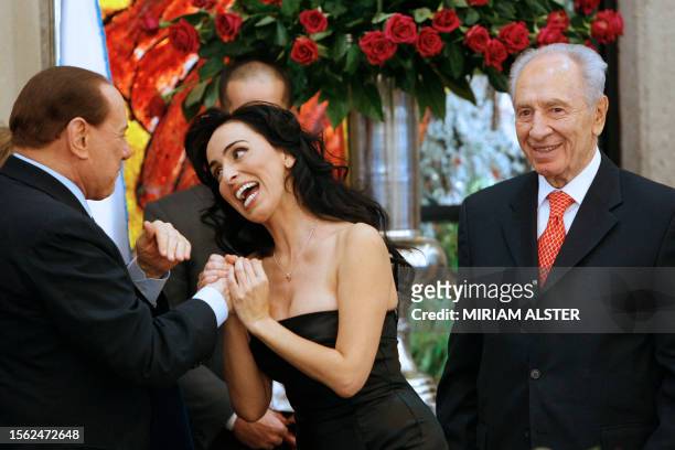 Israeli singer Rita greets Italian Prime Minister Silvio Berlusconi alongside Israel's President Shimon Peres after her performance at a lunch held...