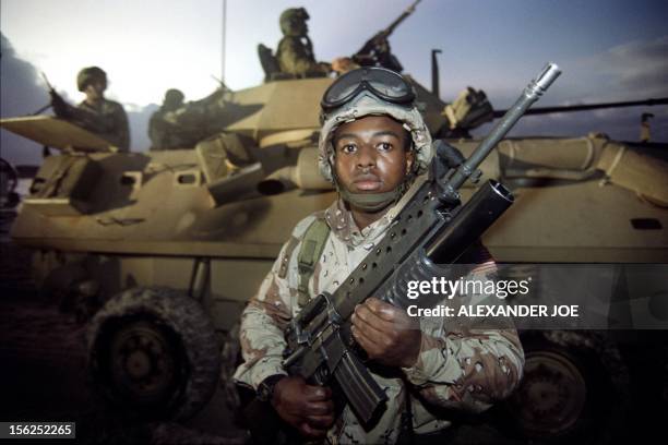 Marine holds up his gun after disembarking from a landing craft on the beach near Mogadishu airport on December 09, 1992 as US military units take...