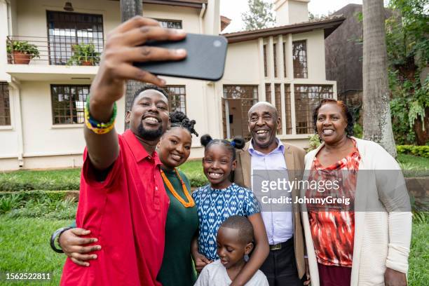 une famille souriante de nairobi prend un selfie dans le jardin de la maison - east africa photos et images de collection