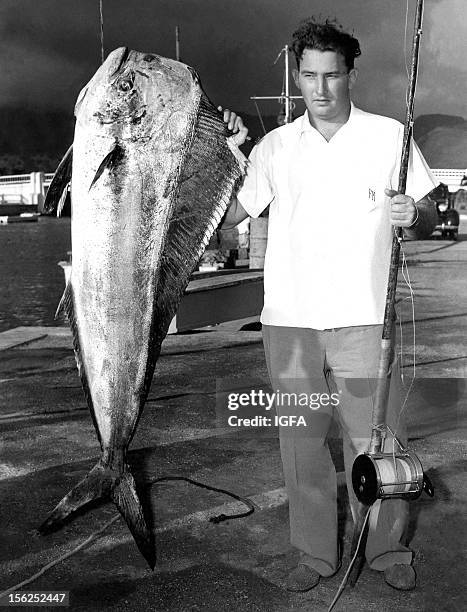 Man stands next to a 67.5 pound dolphinfish caught near Sunset Marina in Wai'anae, Oahu, Hawaii on August 19, 1940.