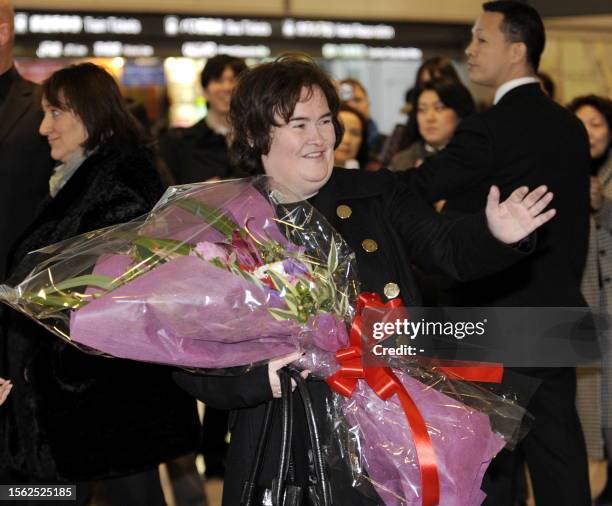 Scottish singer Susan Boyle is all smiles as she receives a flower bouquet upon her arrival at the Narita International Airport in Narita city in...