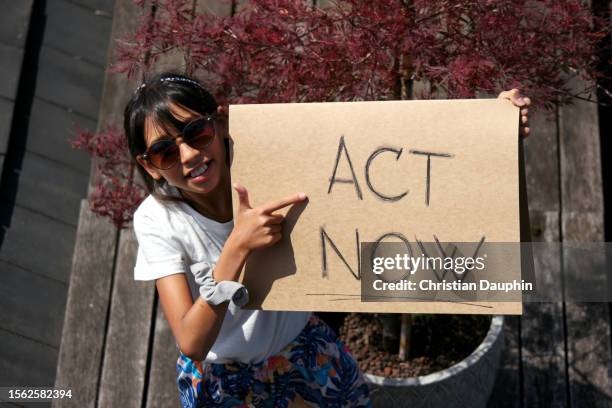 mixed-race teenager fights to save the environment and protest climate change.
she is holding cardboard signs. - adulte d'âge moyen stock pictures, royalty-free photos & images