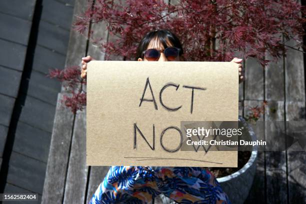 mixed-race teenager fights to save the environment and protest climate change.
she is holding cardboard signs. - adulte d'âge moyen stock pictures, royalty-free photos & images