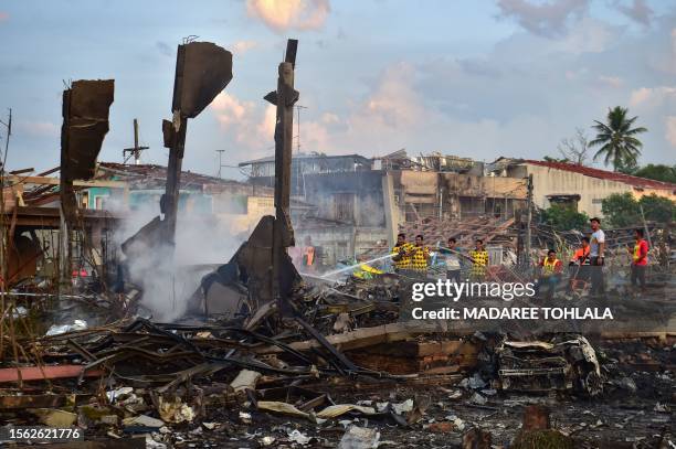 Thai firefighters put out embers around destroyed homes after an explosion ripped through a firework warehouse, killing nine people and injuring more...