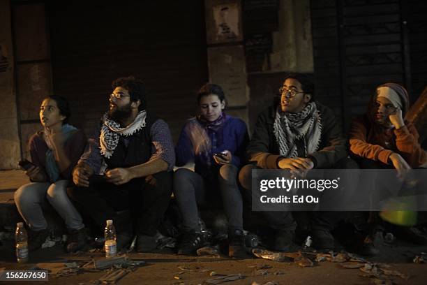 Activists Hana El-Rakhawi Omar Shamy Menna Elshishini and Hossam Shukrallah, 19 sit on the curb in Cairo, Egypt as clashes with the police continue a...