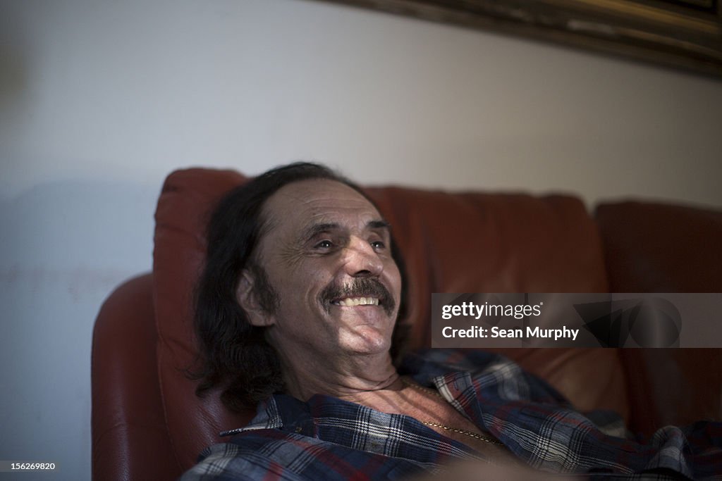 Elderly man smiling off camera sitting on a couch