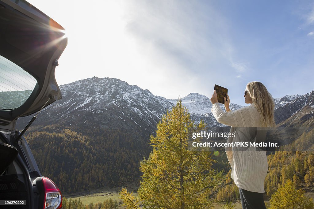 Woman takes picture with digital tablet, mtns