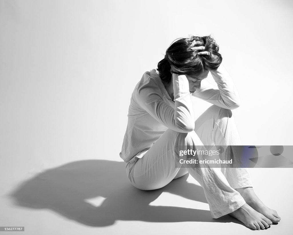 Sad Woman Sitting on Floor and Holding Head in Hands