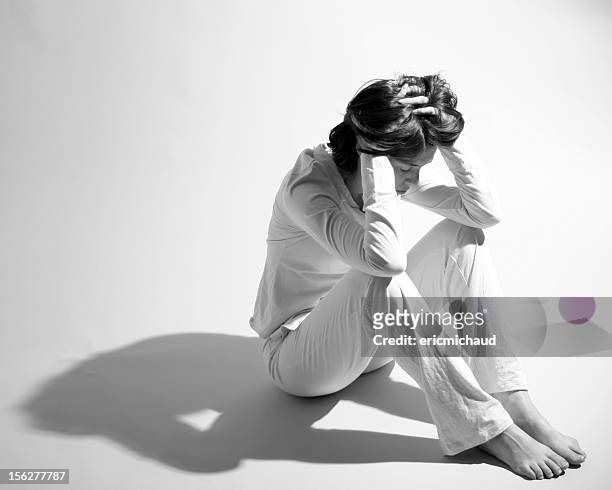sad woman sitting on floor and holding head in hands - woman suicide stock pictures, royalty-free photos & images