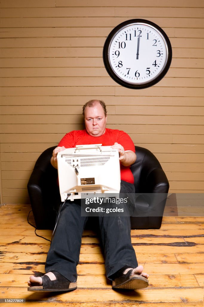 Triste homem sentado no sofá e assistir televisão em Miniatura