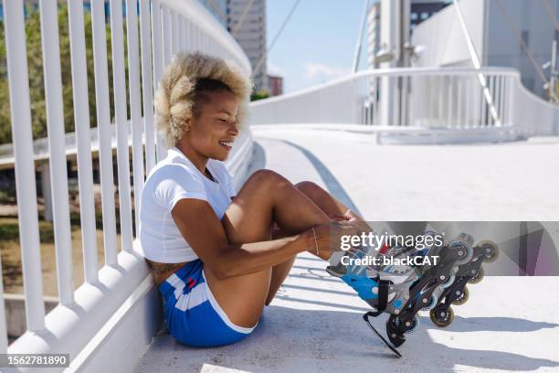 woman puts on roller skates in the city - inline skate stock pictures, royalty-free photos & images