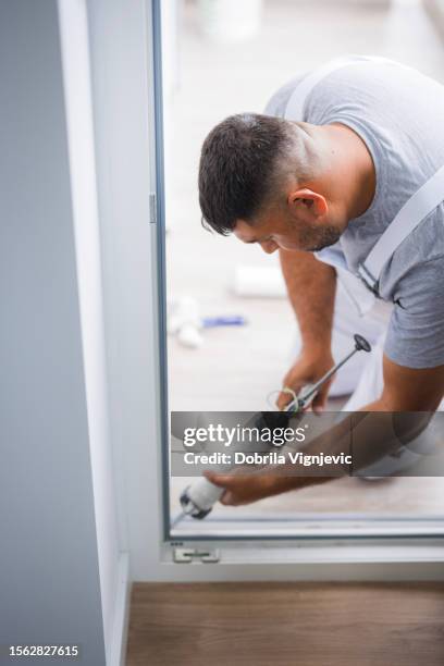 construction worker sealing window with caulk - caulk stockfoto's en -beelden