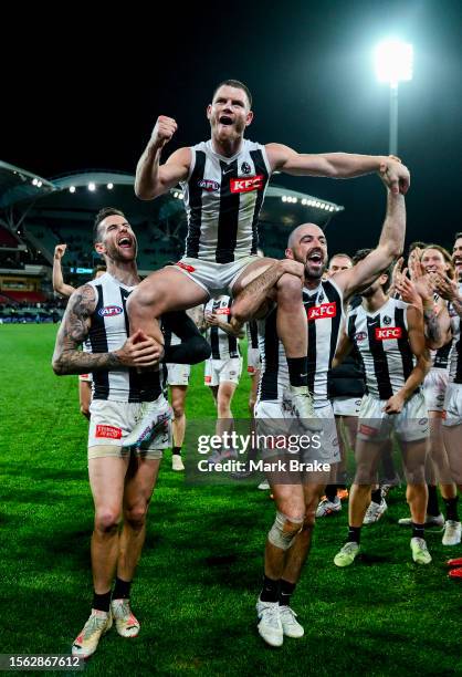 Taylor Adams of the Magpies is chaired off by Jeremy Howe of the Magpies and Steele Sidebottom of the Magpies for his 200th during the round 19 AFL...