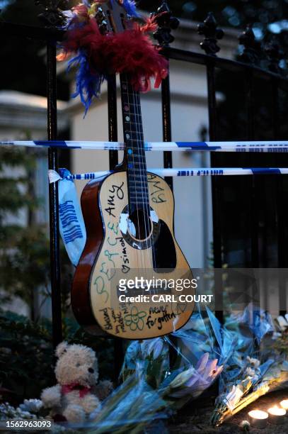 Guitar with messages written on it is left with flowers and notes near the house in north London where the body of English pop star Amy Winehouse was...