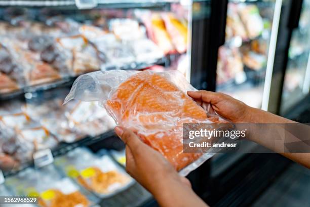 close-up on a woman holding a salmon at the supermarket - fillet stock pictures, royalty-free photos & images