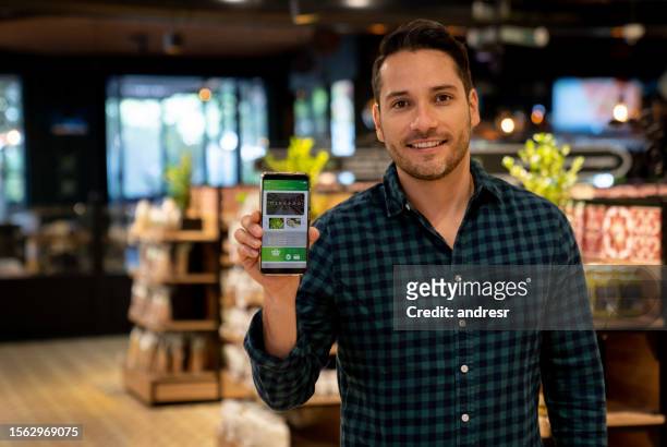 cliente en el supermercado usando una aplicación de comercio electrónico en su teléfono celular - mid adult men fotografías e imágenes de stock