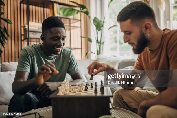 amigos varones jugando al ajedrez - ajedrez fotografías e imágenes de stock