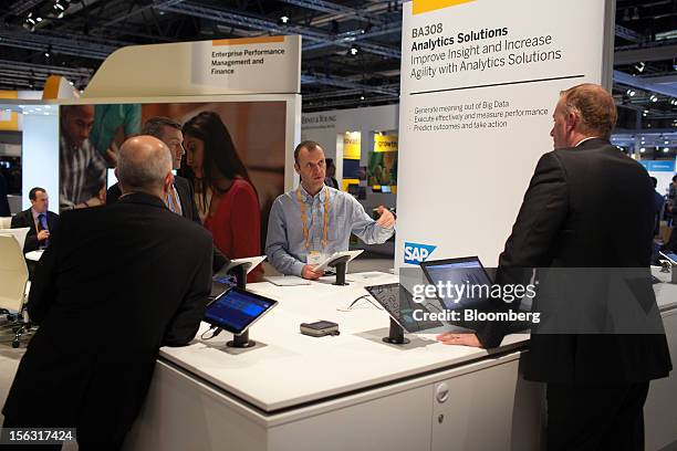 Visitors receive information from a specialist at a display of tablet devices on an SAP AG analytics solutions pavilion on the opening day of the...