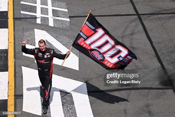 Kyle Busch, driver of the Zariz Transport Chevrolet, waves a flag in celebration of Kyle Busch Motorsports' 100th win in the NASCAR Truck Series...