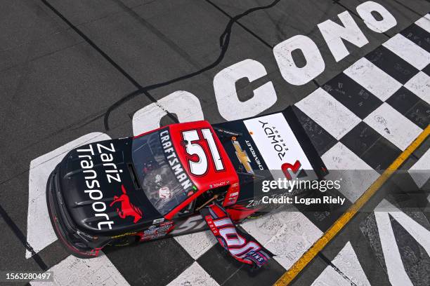 Kyle Busch, driver of the Zariz Transport Chevrolet, drives with a flag in celebration of Kyle Busch Motorsports' 100th win in the NASCAR Truck...