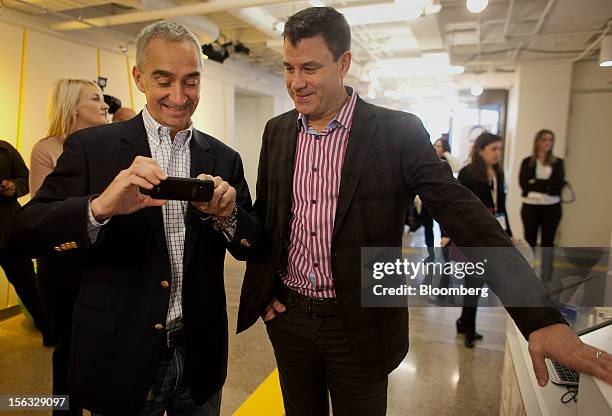 Patrick Pichette, chief financial officer of Google Inc., left, shows Chris O'Neil, managing director of Google Inc. Canada, a photo on his phone...